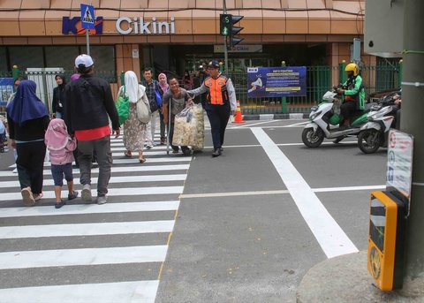 Pejalan kaki melintasi penyeberangan pejalan kaki yang dikontrol lampu lalu lintas atau dikenal sebagai persimpangan pelikan (pelican crossing) di  sisi timur Stasiun Cikini, Jakarta, Senin (15/09/2025).