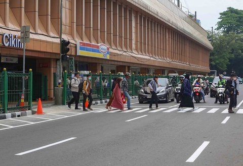 Pejalan kaki melintasi penyeberangan pejalan kaki yang dikontrol lampu lalu lintas atau dikenal sebagai persimpangan pelikan (pelican crossing) di  sisi timur Stasiun Cikini, Jakarta, Senin (15/09/2025).