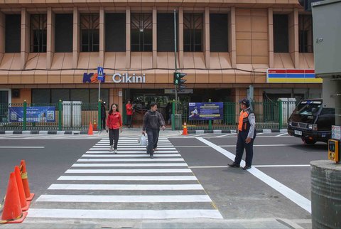 Pejalan kaki melintasi penyeberangan pejalan kaki yang dikontrol lampu lalu lintas atau dikenal sebagai persimpangan pelikan (pelican crossing) di  sisi timur Stasiun Cikini, Jakarta, Senin (15/09/2025).