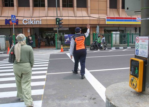 Pejalan kaki melintasi penyeberangan pejalan kaki yang dikontrol lampu lalu lintas atau dikenal sebagai persimpangan pelikan (pelican crossing) di  sisi timur Stasiun Cikini, Jakarta, Senin (15/09/2025).