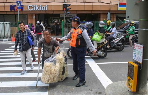 Pejalan kaki melintasi penyeberangan pejalan kaki yang dikontrol lampu lalu lintas atau dikenal sebagai persimpangan pelikan (pelican crossing) di  sisi timur Stasiun Cikini, Jakarta, Senin (15/09/2025).