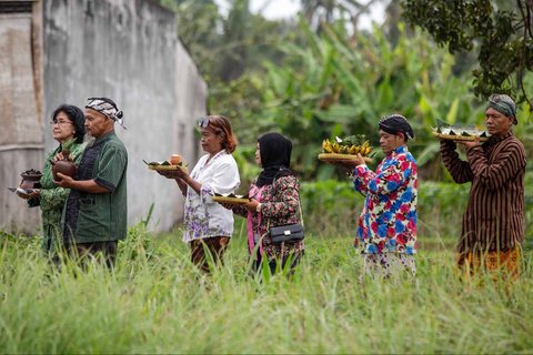 Warga membawa sesaji saat prosesi adat Labuh Sawah (Megawe) di Bulak Kenari, Kregolan, Margomulyo, Seyegan, Sleman, D.I Yogyakarta, Selasa (16/9/2025)