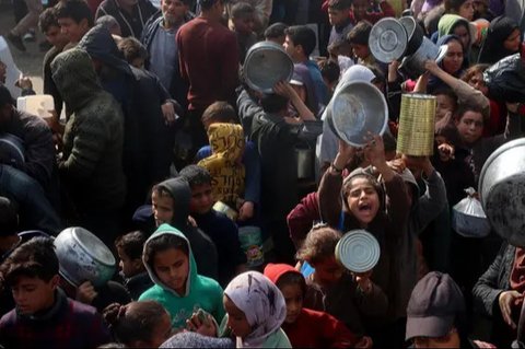 Seorang wanita Palestina bersama seorang anak berdiri di depan puing-puing rumah yang hancur akibat pengeboman Israel di Khan Yunis di Jalur Gaza selatan pada 6 Maret 2024. (Foto oleh AFP)