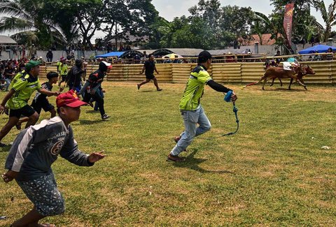 Warga memberikan semangat kepada peserta lomba karapan sapi Karapan Sapi di Bangkalan, Pulau Madura, Jawa Timur, Minggu (21/09/2025).