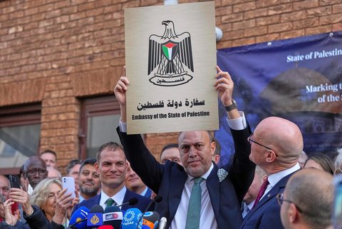 Duta Besar untuk Misi Palestina di Inggris Husam S. Zomlot memegang lambang kedutaan Palestina dalam sebuah upacara di Misi Palestina di London, Senin (22/09/2025).