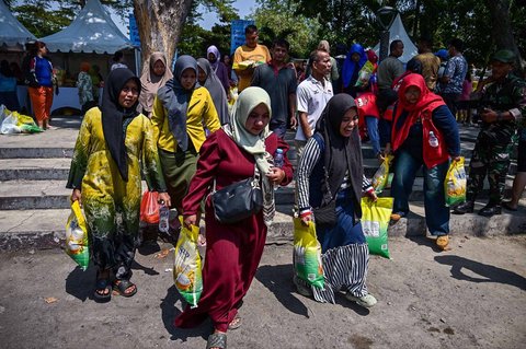 Warga usai membeli kebutuhan pokok saat kegiatan Gerakan Pangan Murah (GPM)   di Taman 10 Nopember, Tambaksari, Surabaya, Selasa (23/9/2025).