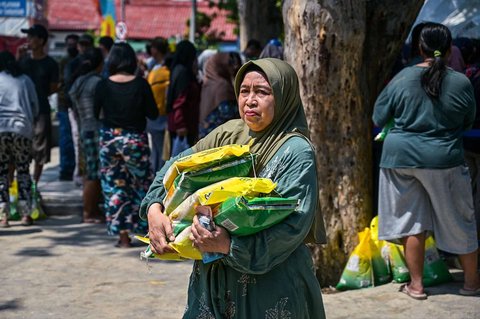 Warga usai membeli kebutuhan pokok saat kegiatan Gerakan Pangan Murah (GPM)   di Taman 10 Nopember, Tambaksari, Surabaya, Selasa (23/9/2025).