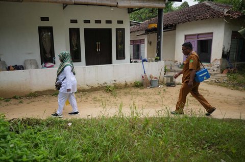 Paramedis Indra Kurniawan (kanan) membawa kotak pendingin berisi vaksin campak bersama rekannya, Fera Purnamasari, saat kampanye vaksinasi dari rumah ke rumah di Sumenep, Madura, Jawa Timur (08/09/2025).