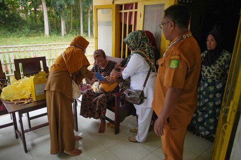 Petugas kesehatan Siti Nurjanah (kiri) menyuntikkan vaksin campak kepada seorang anak, dibantu rekannya, saat kampanye vaksinasi door-to-door di Sumenep, Madura, Jawa Timur (08/09/ 2025).
