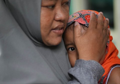 Seorang anak dihibur ibunya saat menerima vaksin campak saat  kampanye vaksinasi pasca-wabah di sebuah TK di Sumenep, Sumenep, Madura, Jawa Timur (08/09/ 2025).
