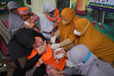 Petugas kesehatan memberikan suntikan campak kepada seorang anak saat  kampanye vaksinasi pasca-wabah di sebuah TK di Sumenep, Madura, Jawa Timur (08/09/ 2025).