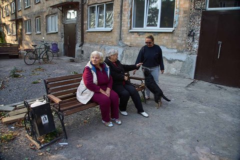 Warga bermain dengan anjing di dekat apartemen yang baru direnovasi usai rusak akibat pertempuran di Avdiivka, Donetsk, Ukraina, Sabtu (27/9/2025). Kota ini kini berada di bawah kendali Rusia.