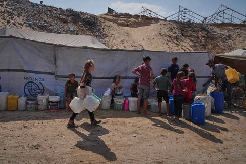 Warga Palestina yang mengungsi mengantre untuk mengambil air di sebuah kamp tenda di Muwasi, wilayah yang ditetapkan Israel sebagai zona aman, di Khan Younis, Jalur Gaza selatan, Senin (29/09/2025).