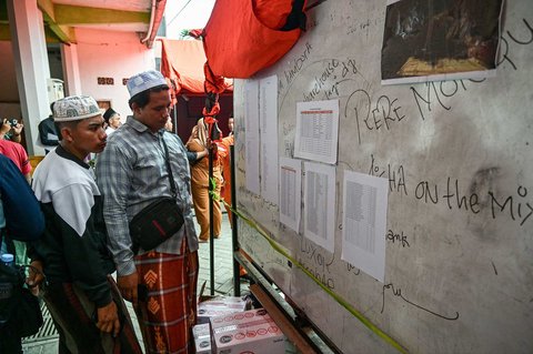 Keluarga santri melihat daftar nama di papan sementara operasi SAR di Pondok Pesantren Al Khoziny di Sidoarjo, Jawa Timur, Selasa (30/09/2025).