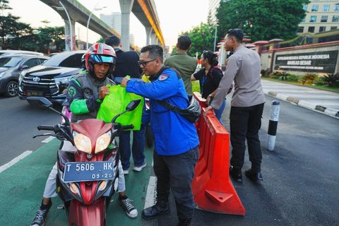 Buruh bersama  anggota Polri membagikan paket sembako di perempatan depan Mabes Polri, Jalan Trunojoyo, Jakarta, Kamis sore (05/09/2025).