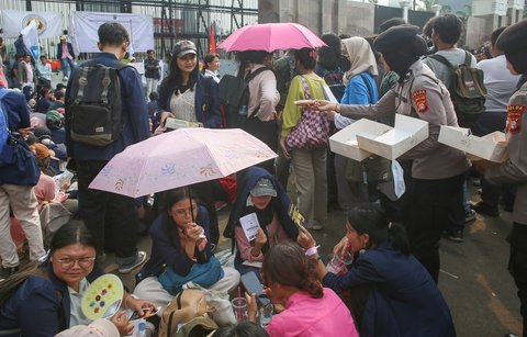 Polwan membagikan roti saat mahasiswa mengatasnamakan Koalisi Masyrakat Sipil  menggelar aksi bertema 'Piknik Nasional Rakyat' di depan Gedung DPR RI, Senayan, Jakarta Pusat, Jumat (5/9/2025).