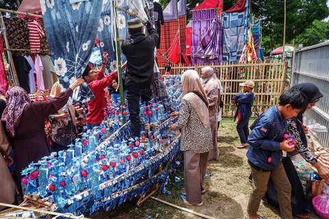Warga mengambil makanan dan beragam peralatan rumah tangga tangga yang dibagikan dari  miniatur perahu Pinisi di Desa Damai, Sulawesi Selatan, Minggu (07/09/2025).