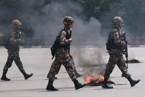 Tentara bersenjata senapan serbu berjalan melewati jalan dekat kantor Partai Kongres Nepal yang terbakar dalam aksi protes untuk mengecam tindakan keras mematikan yang dilakukan polisi terhadap demonstran di Kathmandu, Selasa (9/09/2025).