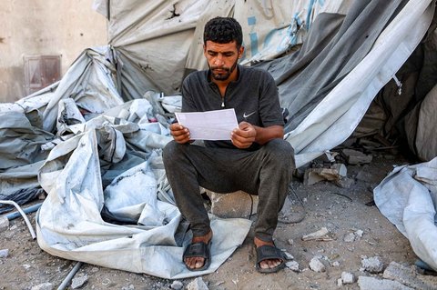 Warga membaca selebaran yang dijatuhkan oleh militer Israel yang menyerukan evakuasi ke selatan menuju al-Mawasi di Kota Gaza, Selasa (09/09/2025).