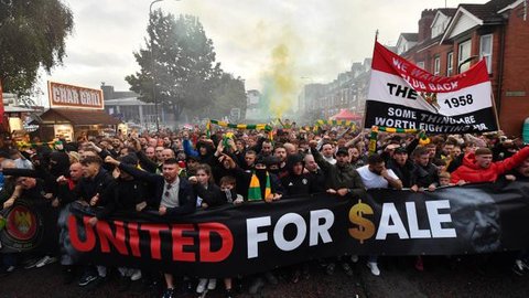 Suporter mengibarkan bendera dan membentangkan spanduk di tribun penonton selama pertandingan Premier League antara Manchester United dan Arsenal di Old Trafford, Manchester, Inggris barat