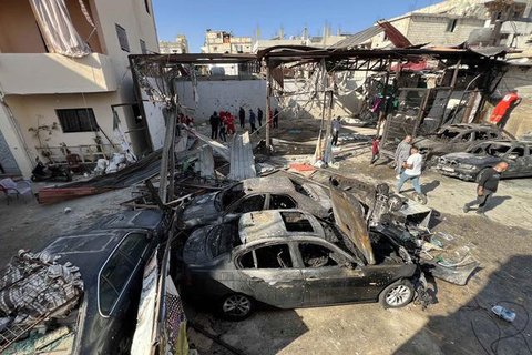 Orang-orang melintas di dekat sebuah mobil yang rusak di lokasi serangan Israel yang menghantam sebuah gedung apartemen di Dahiyeh, wilayah pinggiran selatan Beirut, Lebanon, Minggu, (23/11/2