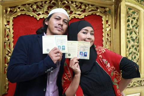 Sementara itu, Santi tampil memikat dalam balutan kebaya putih dengan detail bordir halus. Siluet kebaya yang ringan berpadu dengan kain bernuansa lembut, menghadirkan tampilan pengantin yang