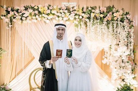 Sementara itu, Santi tampil memikat dalam balutan kebaya putih dengan detail bordir halus. Siluet kebaya yang ringan berpadu dengan kain bernuansa lembut, menghadirkan tampilan pengantin yang