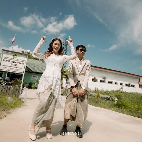 Sementara itu, Santi tampil memikat dalam balutan kebaya putih dengan detail bordir halus. Siluet kebaya yang ringan berpadu dengan kain bernuansa lembut, menghadirkan tampilan pengantin yang