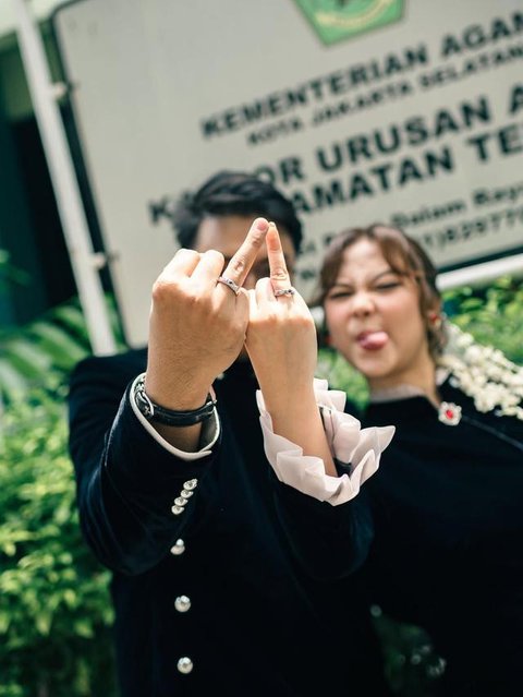 Sementara itu, Santi tampil memikat dalam balutan kebaya putih dengan detail bordir halus. Siluet kebaya yang ringan berpadu dengan kain bernuansa lembut, menghadirkan tampilan pengantin yang