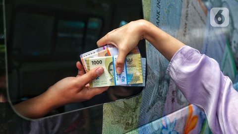 Warga menunjukkan uang rupiah kertas baru emisi 2022 saat penukaran di Pasar Senen, Jakarta, Selasa (23/8/2022). Bank Indonesia (BI) baru saja meluncurkan uang rupiah kertas baru emisi 2022 b