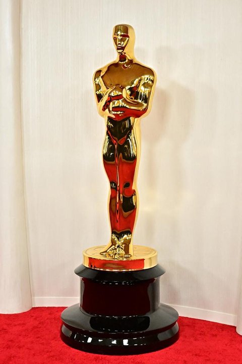 Seorang pria melewati replika patung Oscar pada hari Sabtu, 14 Maret 2026, di jalan dekat Dolby Theatre di Los Angeles, tempat persiapan terus berlangsung untuk upacara Academy Awards ke-98 p