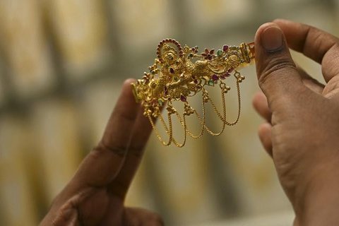 Seorang penjual berjalan melewati kalung emas yang dipajang selama festival Hindu 'Akshaya Tritiya', hari keberuntungan dalam kalender Hindu untuk membeli barang-barang berharga, di ruang