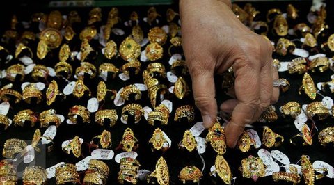 Seorang penjual berjalan melewati kalung emas yang dipajang selama festival Hindu 'Akshaya Tritiya', hari keberuntungan dalam kalender Hindu untuk membeli barang-barang berharga, di ruang