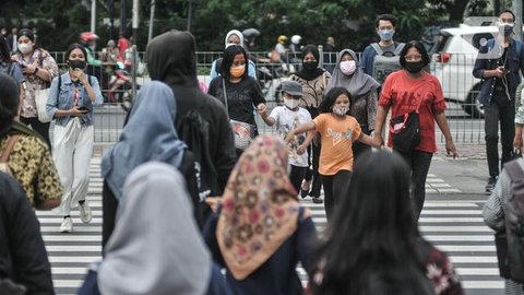 Pekerja melintas di trotoar Jalan Jenderal Sudirman saat jam pulang kantor, Selasa (4/1/2022). PPKM di Jakarta kembali diperpanjang oleh pemerintah pusat terhitung 4-17 Januari 2022 dari sebe
