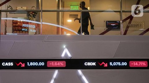 Karyawan melintasi layar yang menampilkan Indeks Harga Saham Gabungan (IHSG) saat acara Penutupan Perdagangan Bursa Efek Indonesia Tahun 2022 di Jakarta, Jumat (30/12/2022). PT Bursa Efek Ind