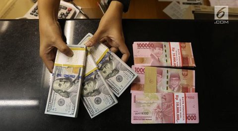 Petugas memperlihatkan uang pecahan US$100 dan rupiah di pusat penukaran uang, Jakarta, , Rabu (12/8/2015). Reshuffle kabinet pemerintahan Jokowi-JK, nilai Rupiah terahadap Dollar AS hingga s