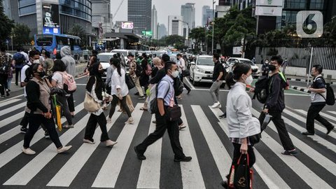 Pekerja melintas di trotoar Jalan Jenderal Sudirman saat jam pulang kantor, Selasa (4/1/2022). PPKM di Jakarta kembali diperpanjang oleh pemerintah pusat terhitung 4-17 Januari 2022 dari sebe