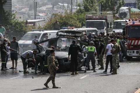 Petugas pertolongan pertama dan warga yang lewat berkumpul di sekitar reruntuhan kendaraan yang menjadi sasaran serangan pesawat tak berawak Israel di kota Jiyeh, Selatan Beirut, pada Rabu 13