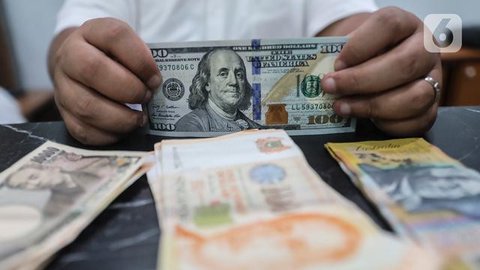 Petugas menunjukkan mata uang dolar dan mata uang rupiah di penukaran uang di Jakarta, Rabu (9/11). Nilai tukar rupiah terhadap dolar Amerika Serikat (AS) pada saat jeda siang ini kian terpur