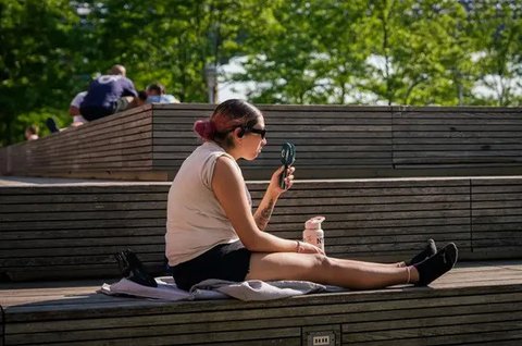 Sejumlah orang berupaya menyejukkan diri saat menunggu kedatangan para tamu pada peragaan koleksi busana pria Prada Spring/Summer 2027 di Milan, Italia, Minggu (21/6/2026). (Dok. Luca Bruno/A
