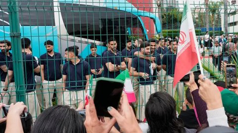 Para penggemar sepak bola di Meksiko menunggu tim Iran sambil mengenakan topi bertuliskan, 'Iran, saudaraku, kau sekarang orang Meksiko', di luar hotel tim di Tijuana, Meksiko, pada 27 Juni 2