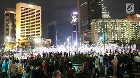 Warga menikmati car free night saat malam pergantian tahun di kawasan Bundaran HI, Jakarta, Senin (31/12). Hujan yang mengguyur Jakarta sejak siang tidak menyurutkan antusias warga menikma