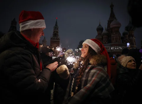 Warga mengenakan topi Santa merayakan Tahun Baru di tepi Lapangan Merah yang ditutup di Moskow , Rusia, Kamis (01/01/2026).