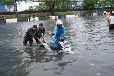 Prajurit TNI Angkatan Laut membantu warga yang motornya mogok  di Jalan Raya Pademangan, Jakarta Utara. Senin (12/01/2026)