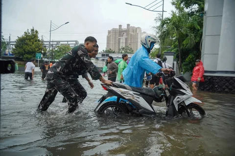 Prajurit TNI Angkatan Laut membantu warga yang motornya mogok  di Jalan Raya Pademangan, Jakarta Utara. Senin (12/01/2026)