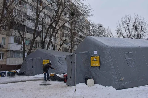 Warga menghangatkan diri di tenda darurat yang disediakan bagi warga setelah serangan udara Rusia terhadap fasilitas energi, yang menyebabkan pemadaman listrik, air, dan pemanas di tengah musim dingin di Kyiv, Ukraina, Selasa (13/01/2026).