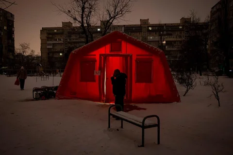 Warga  merokok  di  depan tenda darurat yang disediakan bagi warga setelah serangan udara Rusia terhadap fasilitas energi, yang menyebabkan pemadaman listrik, air, dan pemanas di tengah musim dingin di Kyiv, Ukraina, Selasa (13/01/2026).