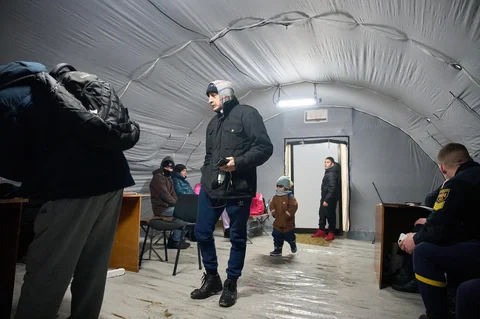 Warga menghangatkan diri di tenda darurat yang disediakan bagi warga setelah serangan udara Rusia terhadap fasilitas energi, yang menyebabkan pemadaman listrik, air, dan pemanas di tengah musim dingin di Kyiv, Ukraina, Selasa (13/01/2026).
