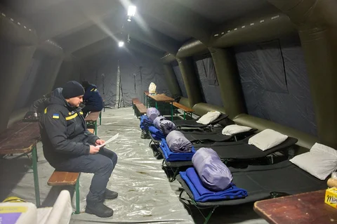 Warga menghangatkan diri di tenda darurat yang disediakan bagi warga setelah serangan udara Rusia terhadap fasilitas energi, yang menyebabkan pemadaman listrik, air, dan pemanas di tengah musim dingin di Kyiv, Ukraina, Selasa (13/01/2026).