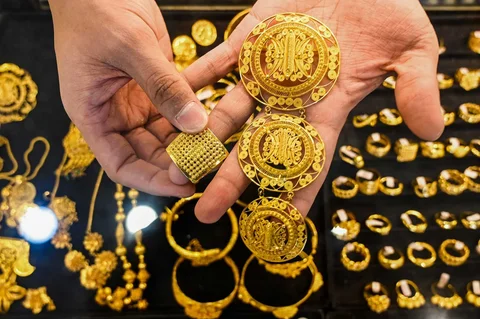 Seorang karyawan memegang beberapa perhiasan emas di sebuah toko perhiasan di Banda Aceh, Rabu (14/01/2026).